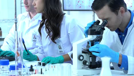 el científico está mirando a través del microscopio con sus colegas que trabajan en un laboratorio moderno o centro médico. concepto de ciencia, desarrollo de pruebas y industria de laboratorio.