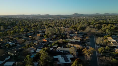 drone flies above rooftops looking back towards canberra’s skyline with the iconic tower visible in the far distance
