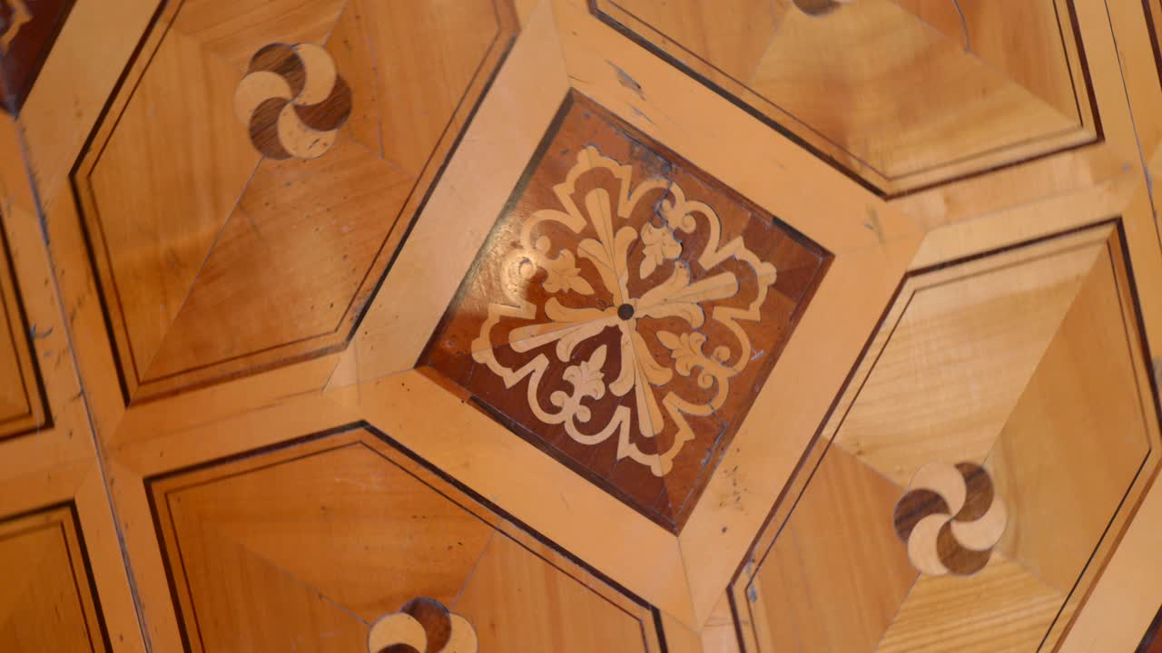 Trieste, Italia: rotación inversa sobre un suelo de parqué ornamentado con incrustaciones geométricas y medallones florales dentro de un palazzo histórico, texturas cálidas de madera y diseño patrimonial refinado