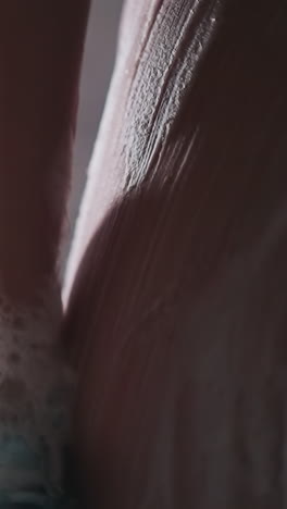 woman washes body side with loofah in shower cabin closeup. lady cleans body skin with foamy mesh sponge in water sprays. pampering and hygiene