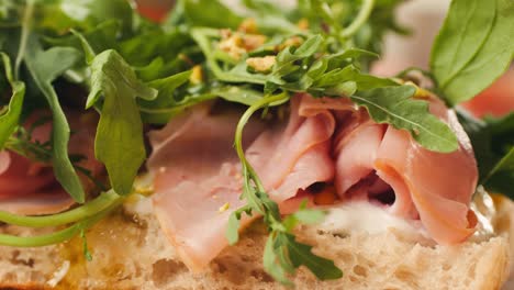 mortadella ham sandwich, traditional italian focaccia filled with thin pesto slices of mortadella, served by chef man in cafe restaurant. macro of traditional italian spanish tapas antipasti.