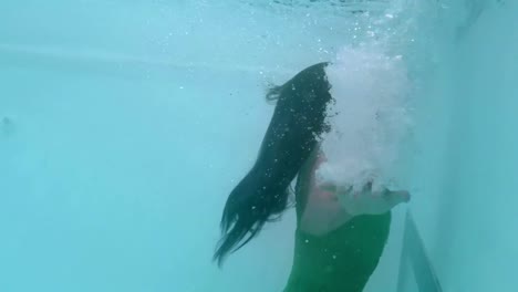 hermosa mujer con vestido verde nadando bajo el agua