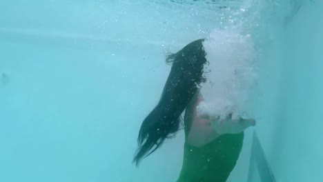 beautiful woman with green dress swimming underwater