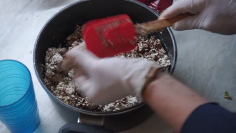 close up of hands wearing latex gloves, mixing ingredients, making energy bars