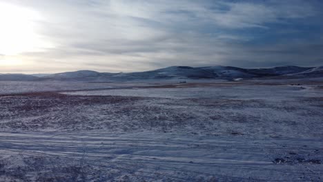 flying over field covered with snow in winter time in canada during sunset