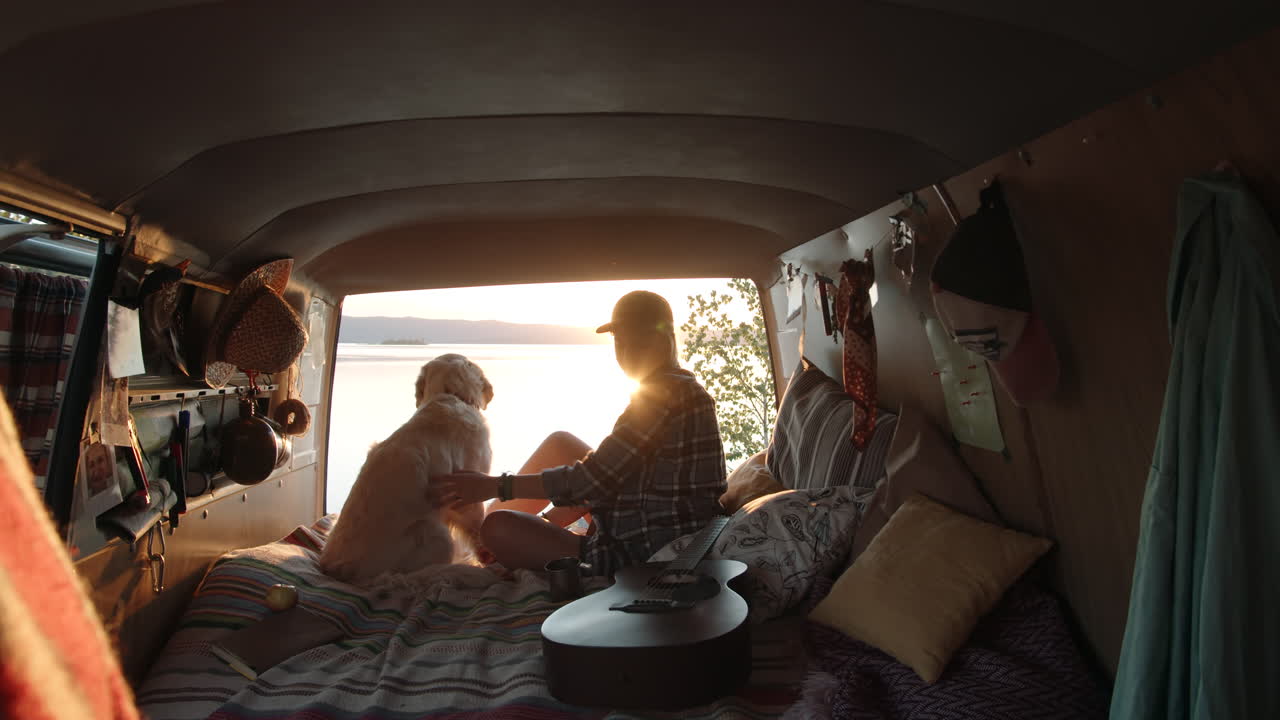 저녁 에 호수변 에 있는 밴 에 앉아 있는 여자 와 개