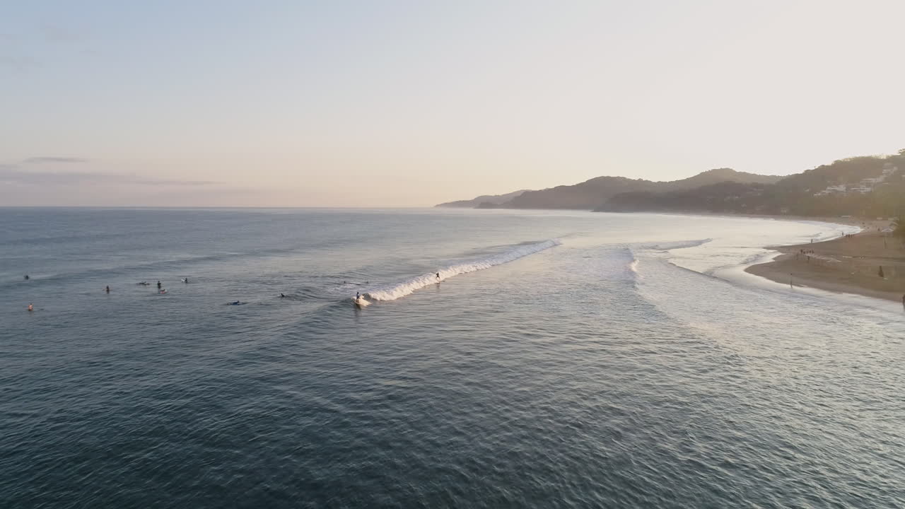 Aerial of paradise sunrise surfing along tropical coast catching waves, 4K