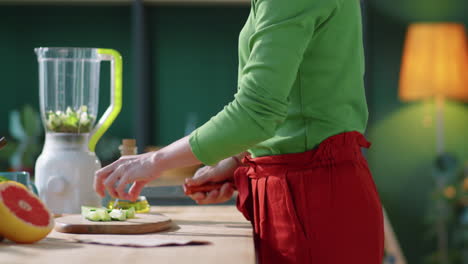 woman cutting cucumber and pitting pieces in blender