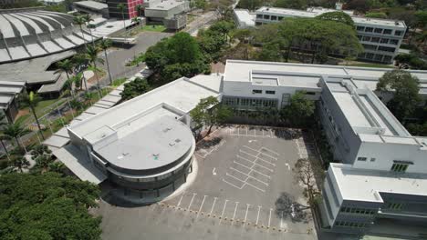 the faculty of medicine at universidad central de venezuela, showing campus buildings and empty parking spaces, aerial view