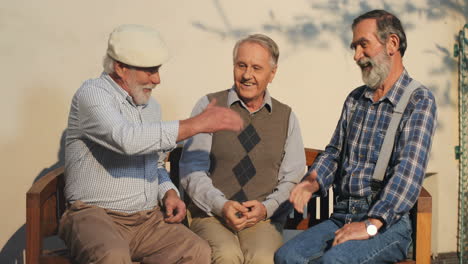 Two-Old-Men-On-Retirement-Sitting-On-The-Bench-And-Chatting,-Then-The-Third-One-Joining-Them