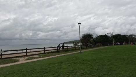 people enjoying a park by the sea under cloudy skies