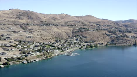 drone flying over houses towards lake and mountains