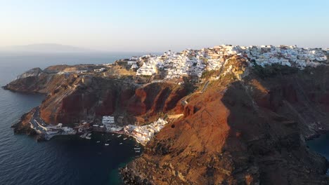 aerial video of famous whitewashed and colourful picturesque village of oia built on a cliff during sunset, santorini island, cyclades, greece