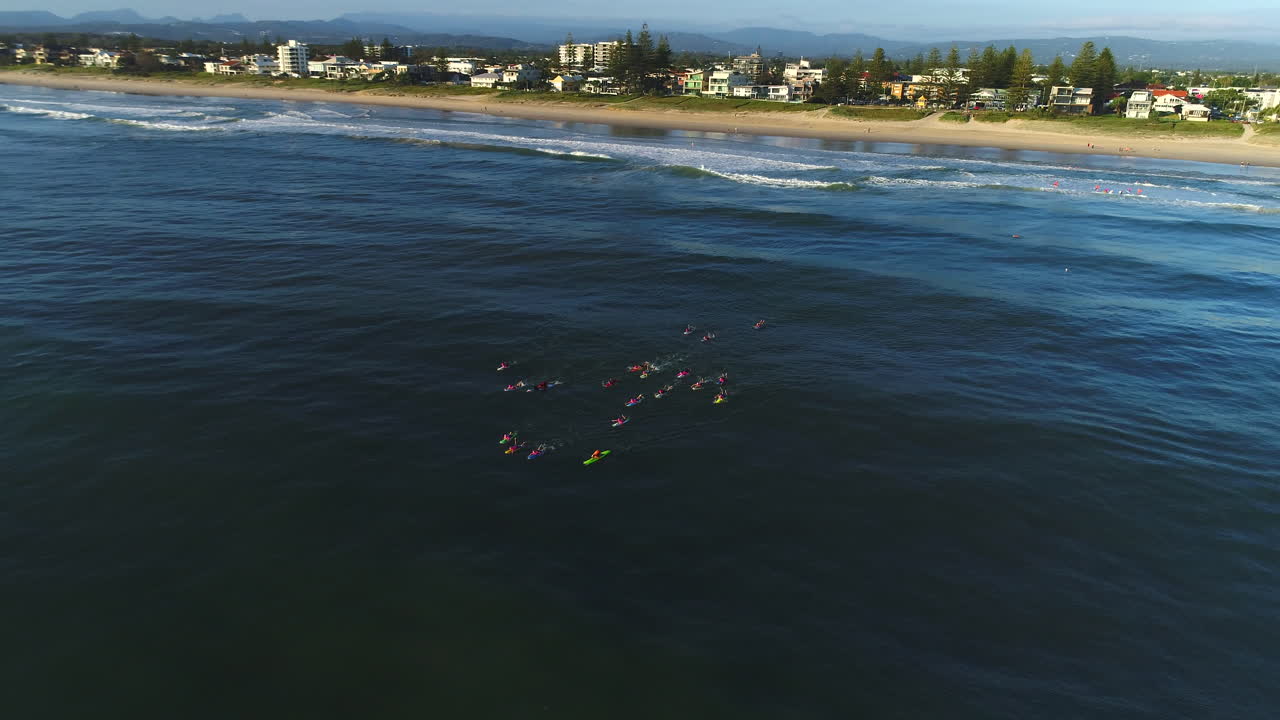 Aerial view of a group of Nippers paddling out into the ocean during a morning training session on a calm day at Mermaid Beach Gold Coast Australia