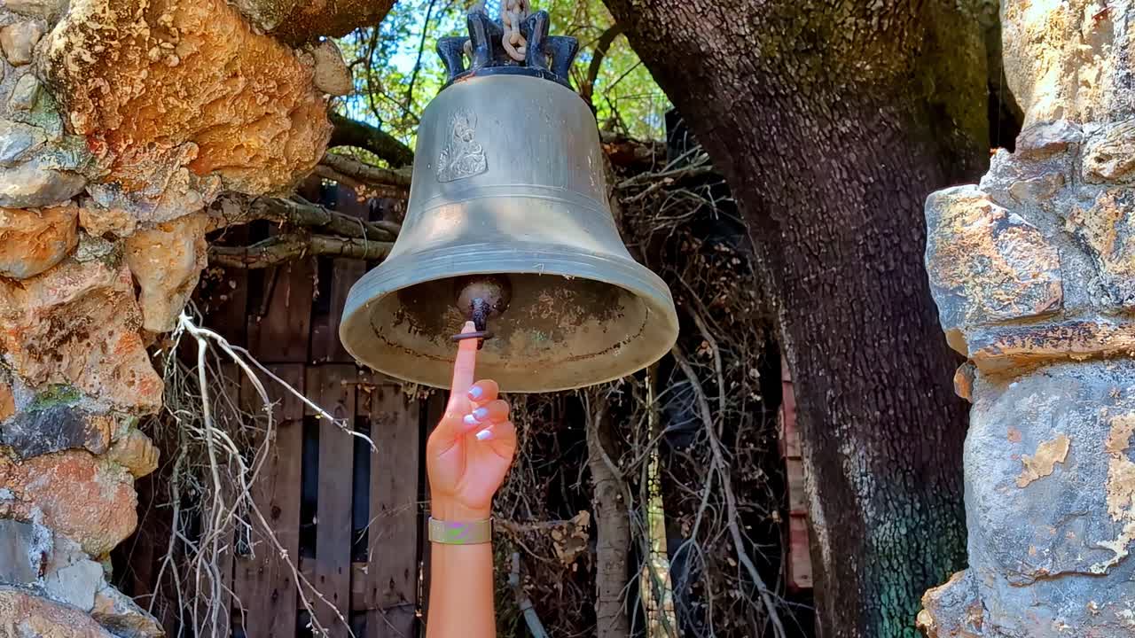 Suonare la campana al parco della mitologia greca situato nel villaggio di Psychro, Creta, Grecia