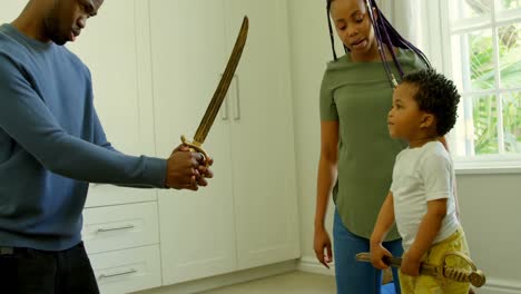 Seitenansicht-Eines-Jungen-Schwarzen-Vaters-Und-Sohnes,-Die-In-Einem-Komfortablen-Zuhause-Mit-Spielzeugschwert-Spielen,-4K