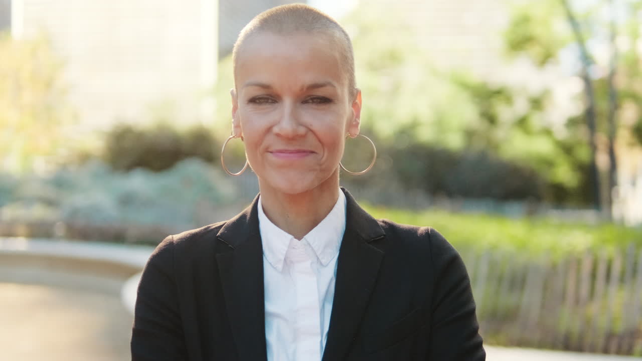 Confident Woman with Shaved Head Smiling at Camera Outdoors