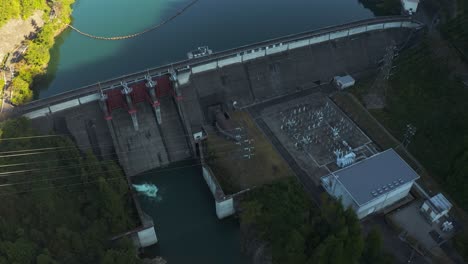 Aerial-view-of-Mazegawa-Dam,-Tilt-reveal-at-sunrise-to-mountains-of-Gifu,-Japan