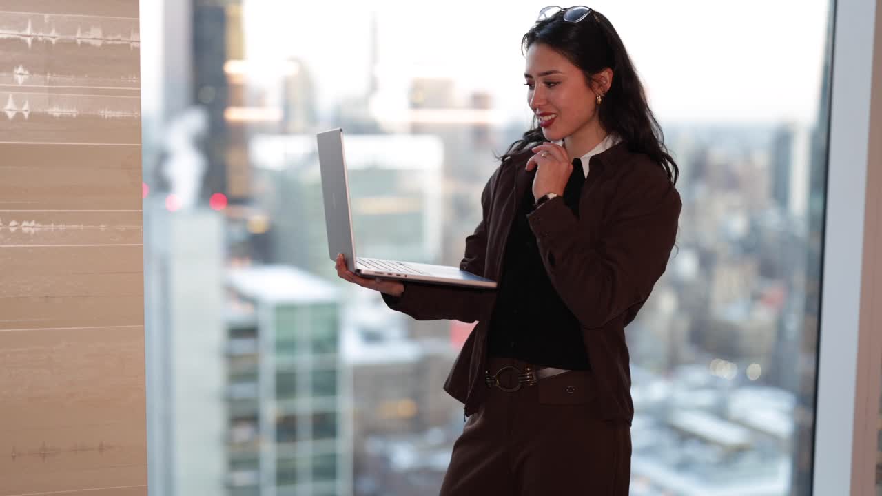 Empresaria trabajando en un portátil con vistas a la ciudad de fondo