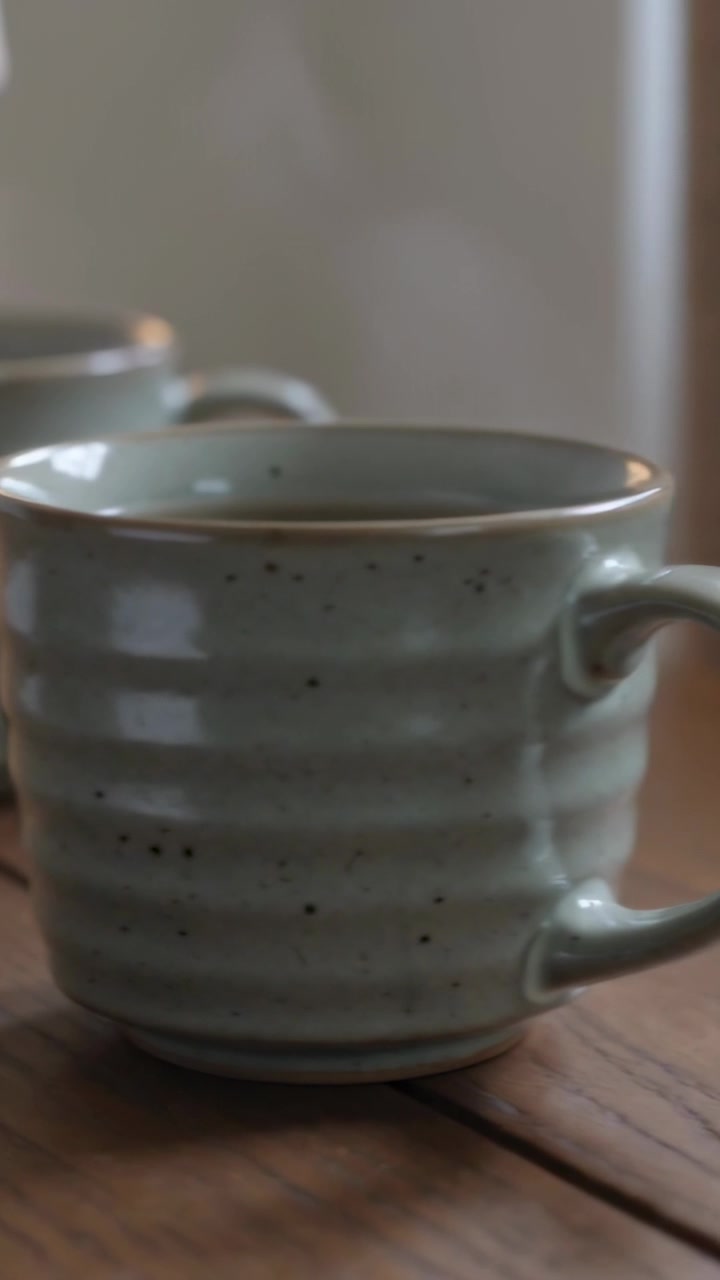 Vertical video: Shifting lens bringing front speckled mug into focus at home, highlighting handle
