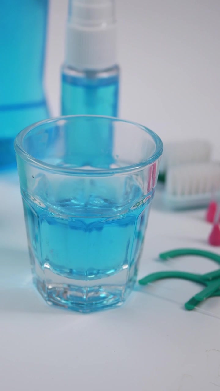 Productos de higiene bucal incluyendo enjuague bucal e hilo dental sobre superficie blanca