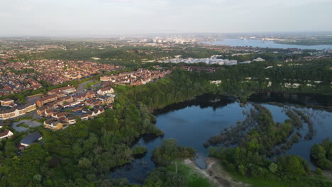 Chafford-gorges-nature-park-with-lush-greenery,-serene-lakes,-and-surrounding-homes,-aerial-view