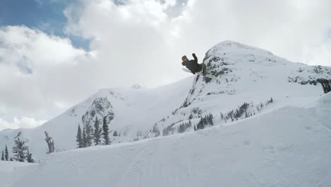 Atleta-Masculino-Girando-Sobre-Un-Gran-Salto-En-El-Backcountry-En-Snowboard