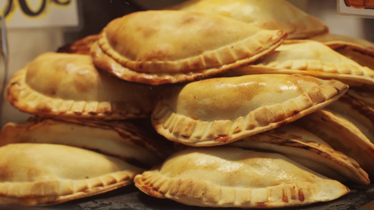 A large stack of freshly baked homemade empanadas beautifully arranged and displayed with a golden, crispy crust