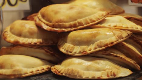 a large stack of freshly baked homemade empanadas beautifully arranged and displayed with a golden, crispy crust