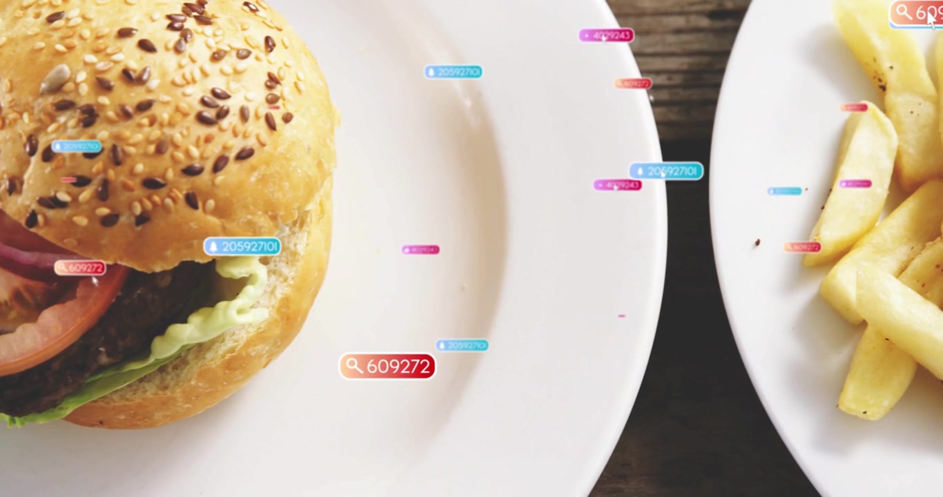 Vertical video: Popping labels drifting at wood table, frame shifting showing sesame burger, fries