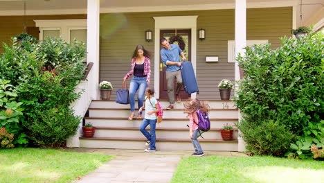 familia con equipaje saliendo de casa para ir de vacaciones