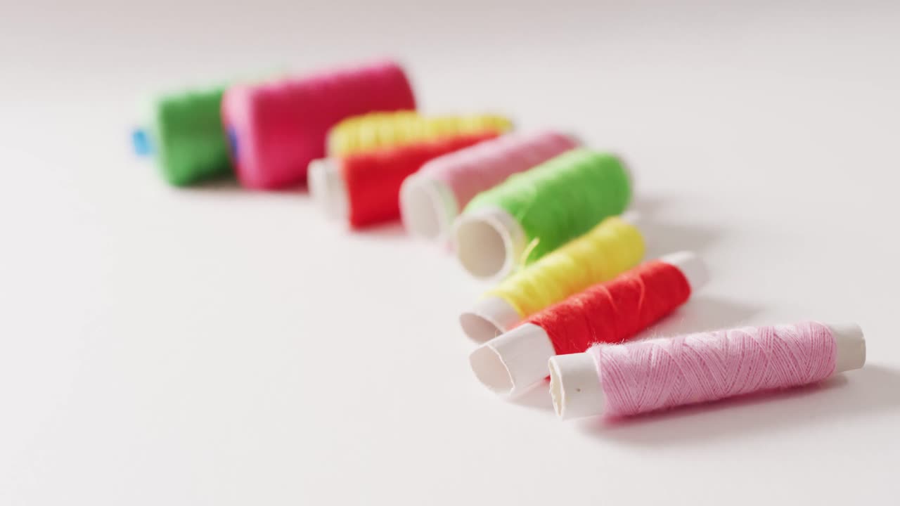 vídeo de bobinas de hilos de bordado de colores en una fila sobre fondo blanco con espacio para copiar