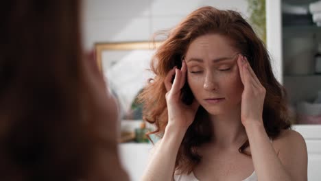 mujer caucásica con un gran dolor de cabeza de pie en el baño.