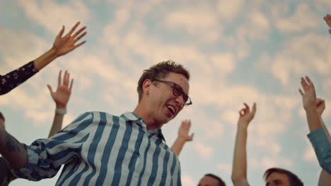 un tipo hipster de primer plano saltando en una discoteca, gente de fiesta divirtiéndose en la azotea.