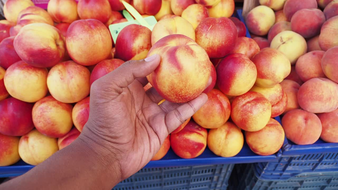 Persona che tiene una nettarina al mercato della frutta