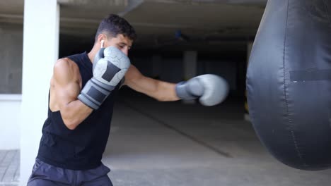 the man executes strong blows in the boxing bag at the parking zone gym