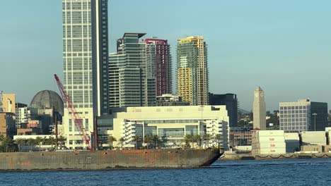 rusty tanker cargo ship beneath the san diego city, california skyline in coronado bay