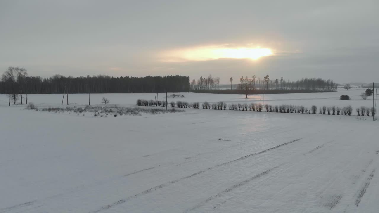paisaje de campo de invierno, drone aéreo volando hacia el atardecer, letonia