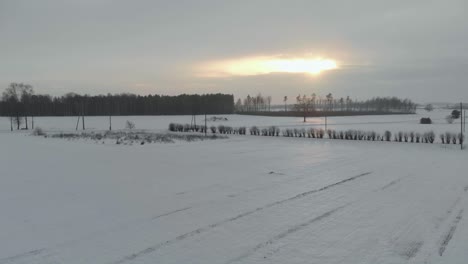 Paisaje-De-Campo-De-Invierno,-Drone-Aéreo-Volando-Hacia-El-Atardecer,-Letonia