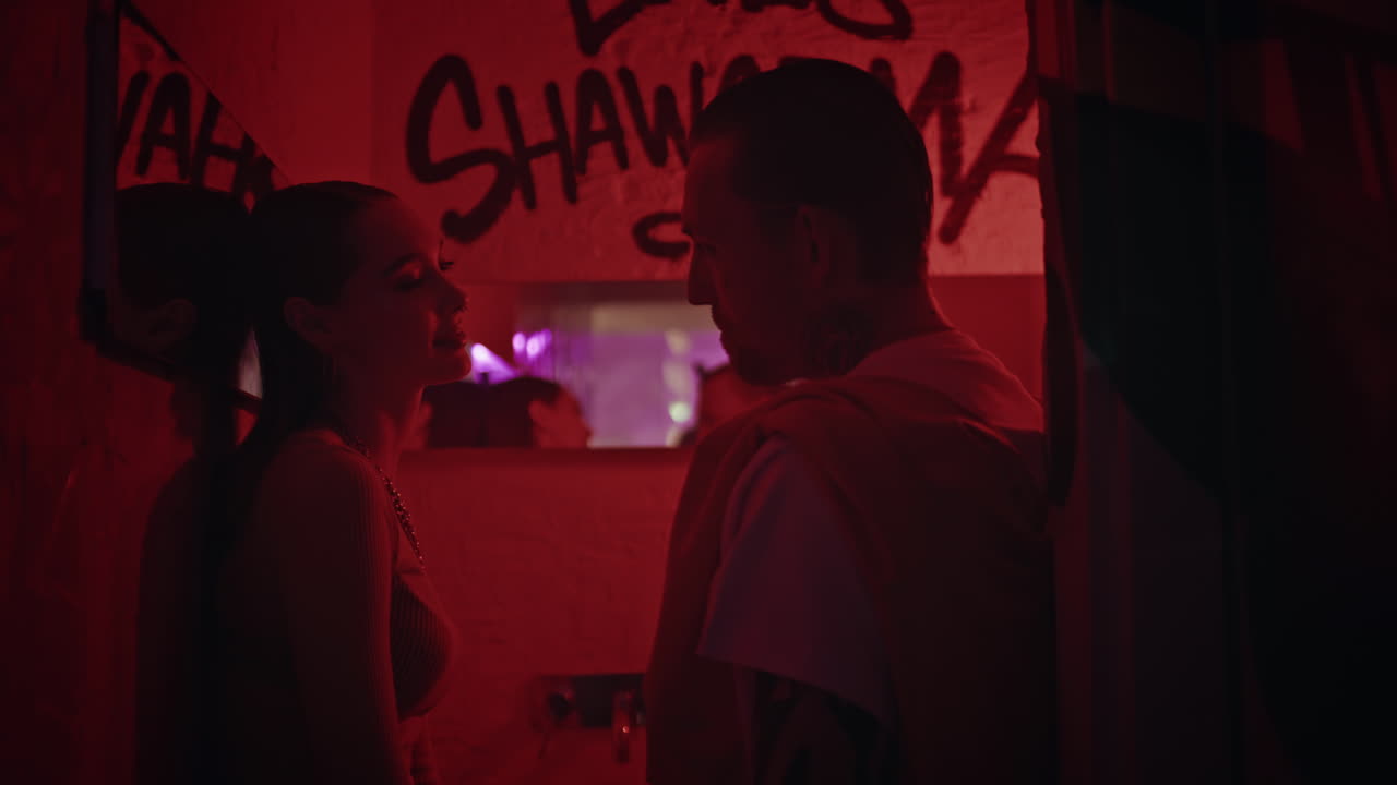 Young couple flirting party at graffiti wall nightclub light backdrop closeup