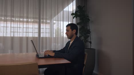 corporate businessman concentrated while working on his laptop in a bright meeting room.