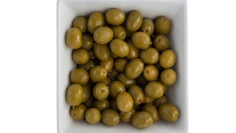 animación de aceitunas verdes en un cuenco sobre un fondo blanco