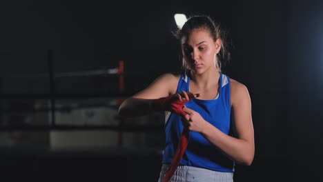 beautiful female boxer pulls red bandages around her arms. steadicam shot