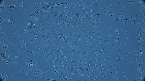 the fascinating movement of particles in a liquid, creating dynamic swirling patterns under a microscope. the observation takes place in a laboratory setting.