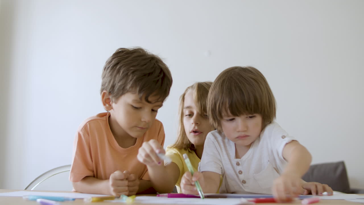 niños caucásicos pintando con marcadores en la sala de estar