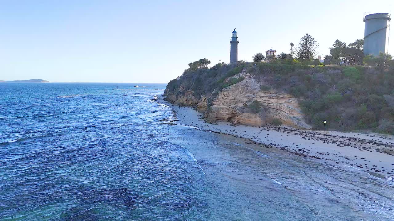 Drone captures stunning views of a coastal lighthouse on Bellarine Peninsula, showcasing rugged cliffs and serene ocean under clear skies
