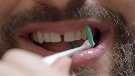 healthy gums focus: man flossing between teeth with floss holder