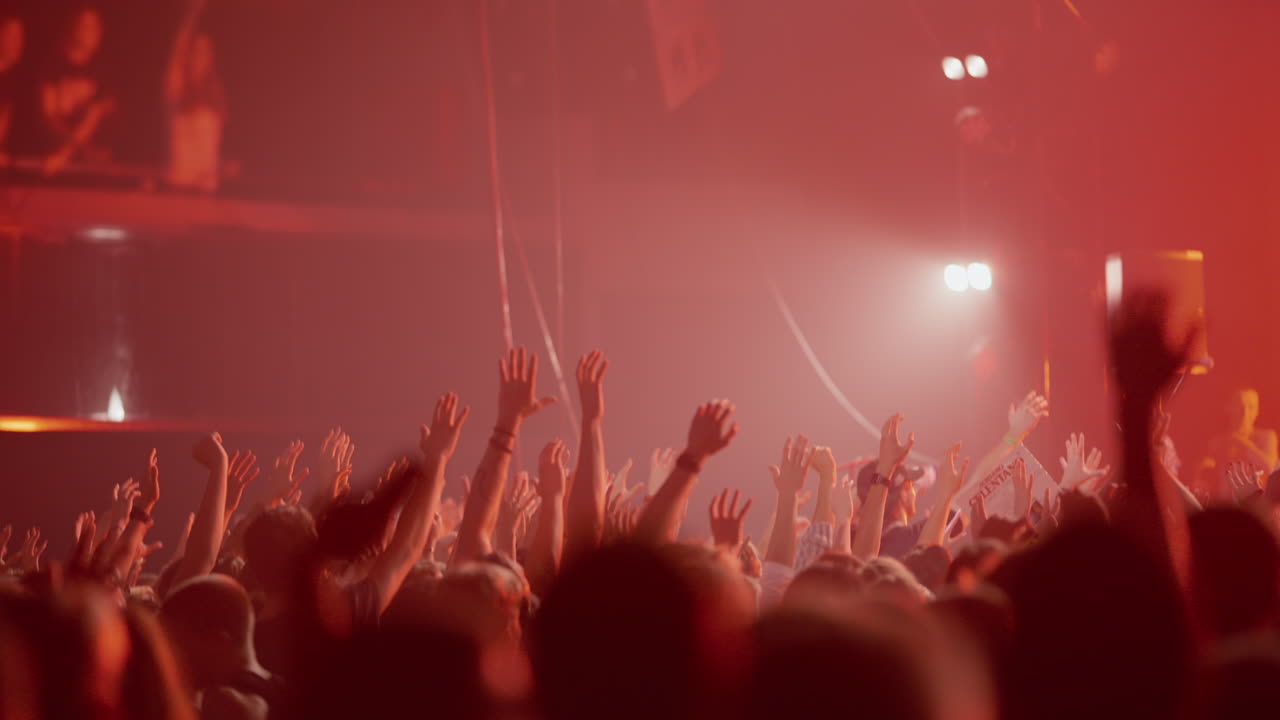 Público lleno de energía levantando las manos en un concierto de música en directo