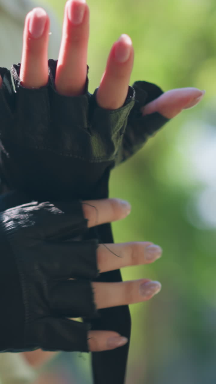 primer plano de individuos al aire libre atando un guante de motociclista en la mano izquierda con un gesto enfocado, el fondo muestra árboles borrosos y vegetación exuberante