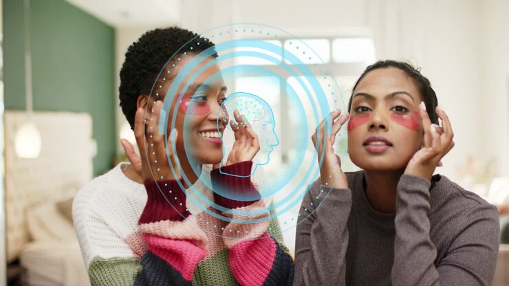 Two women on sofa placing pink eye patches adjusting blue overlay appearing over faces for skincare